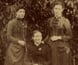 Portrait of one woman, seated, with four girls, one of whom is sitting in a tree. Portrait of one woman, seated, with four girls, one of whom is sitting in a tree.
