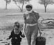 Photograph of a mother and son crossing a drought-effected paddock.
